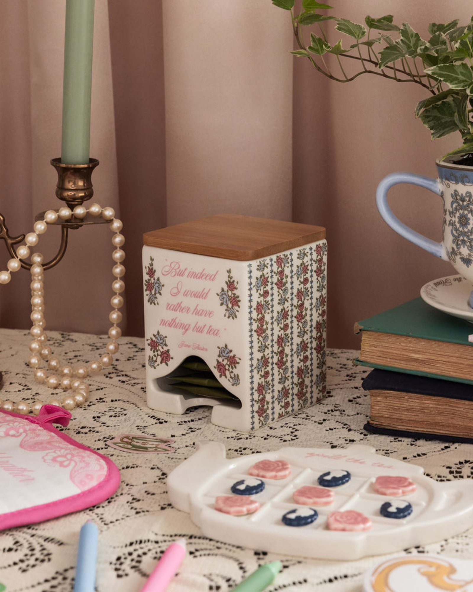 Decorative items on a table including a candle, books, a plant, and a small table with floral design.