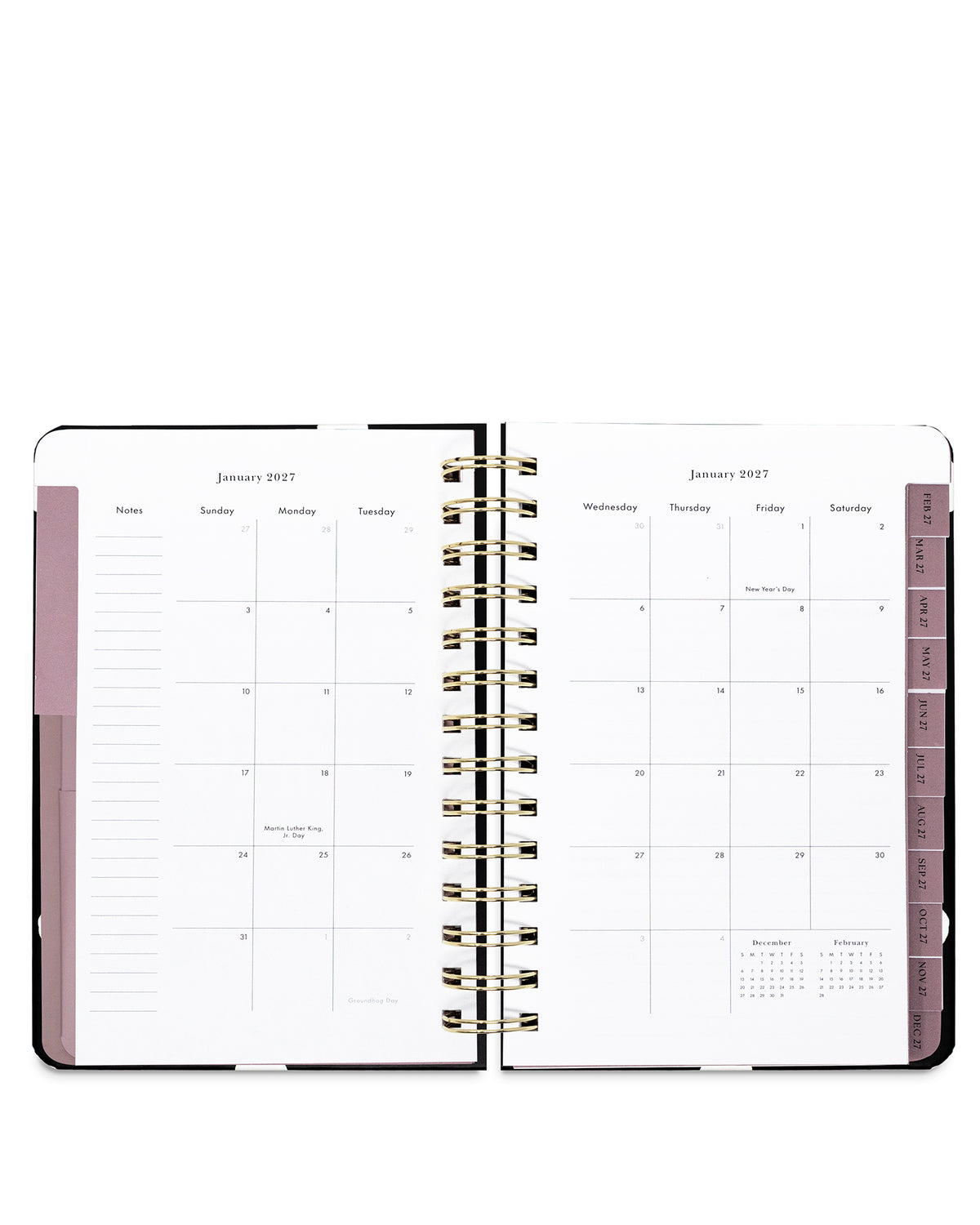An open spiral-bound planner showing a monthly calendar layout in white pages with dusty pink sidebar accents and gold-toned wire binding, photographed on a clean white background.