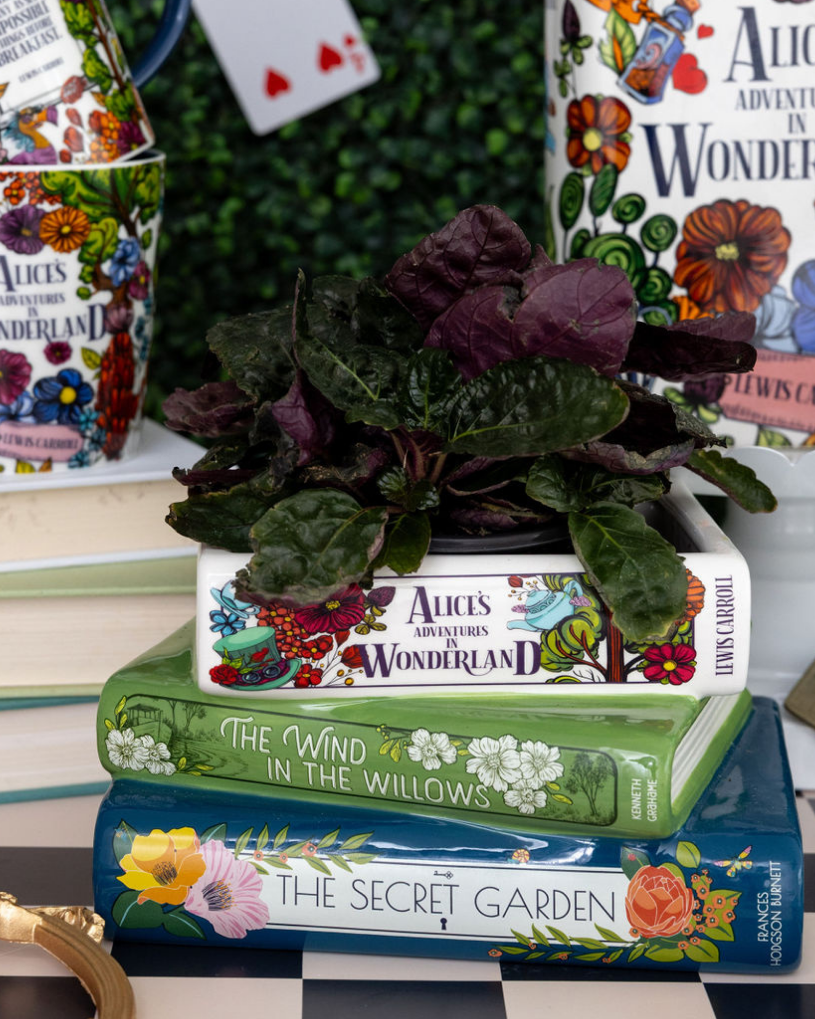 Stack of books with decorative covers featuring illustrations, including 'Alice's Adventures in Wonderland' and 'The Secret Garden'.