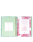 Open planner with green striped and floral design pages on a white background