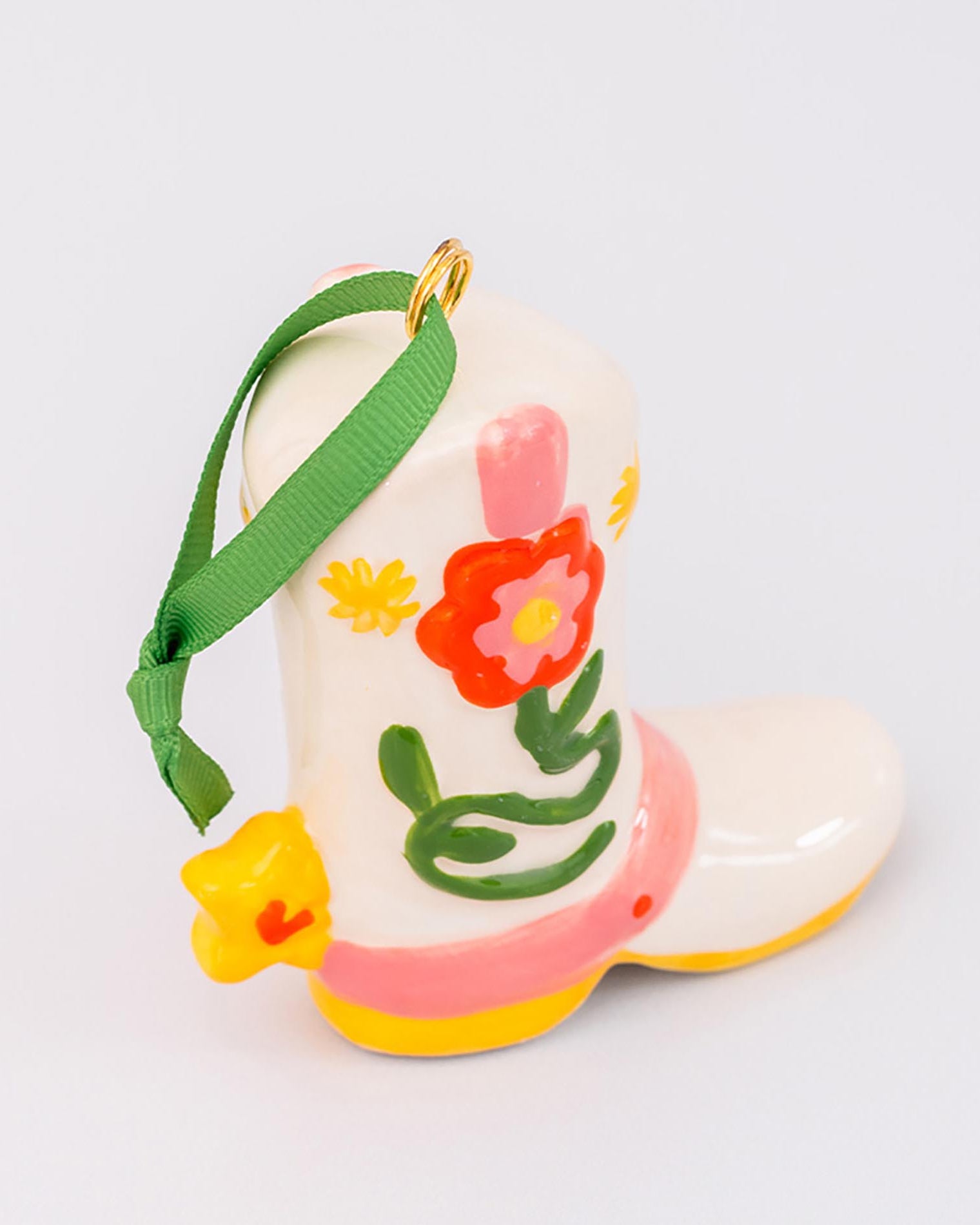 Decorative boot ornament with floral designs and a green ribbon on a light gray background