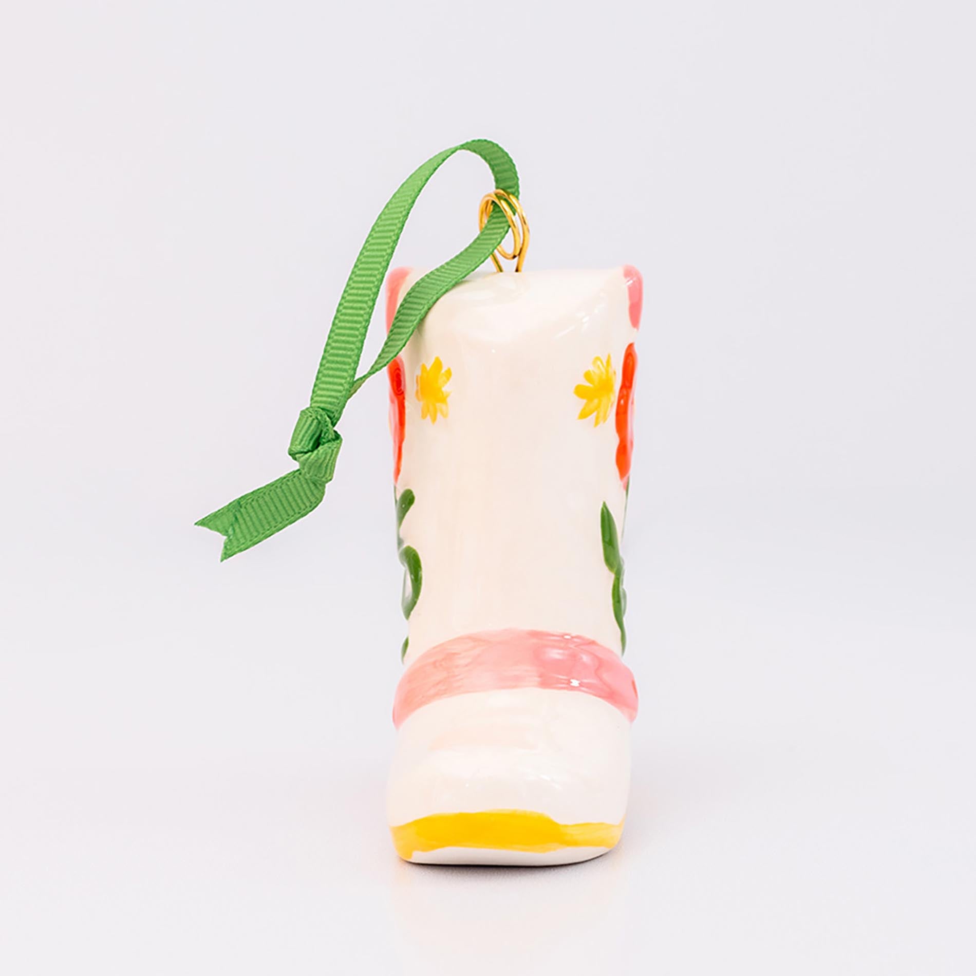 Decorative boot ornament with floral patterns and a green ribbon on a light gray background
