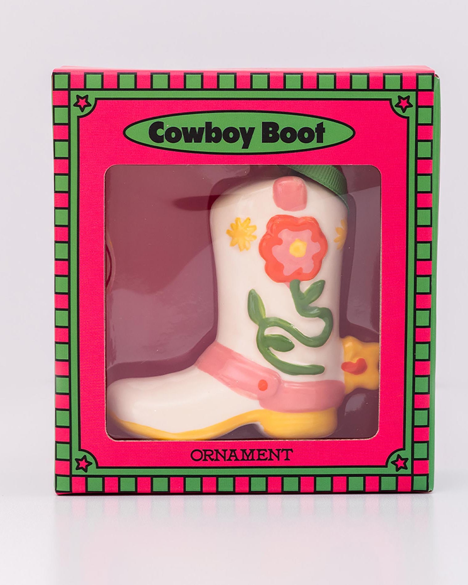 Decorative cowboy boot ornament in a pink box with floral designs on a white background