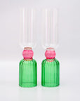 Two green glass bottles with pink stoppers on a white background
