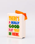 Sideview of ornament with 'THERE'S A REALLY GOOD PLOT TWIST IN HERE' and an orange hanger on a white background
