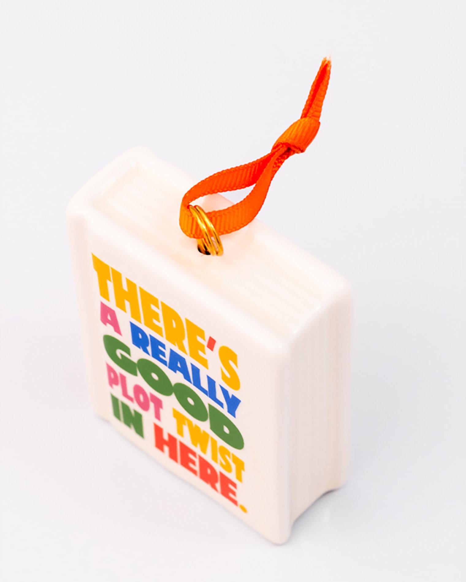 Top view of ornament with 'THERE'S A REALLY GOOD PLOT TWIST IN HERE' and an orange hanger on a white background