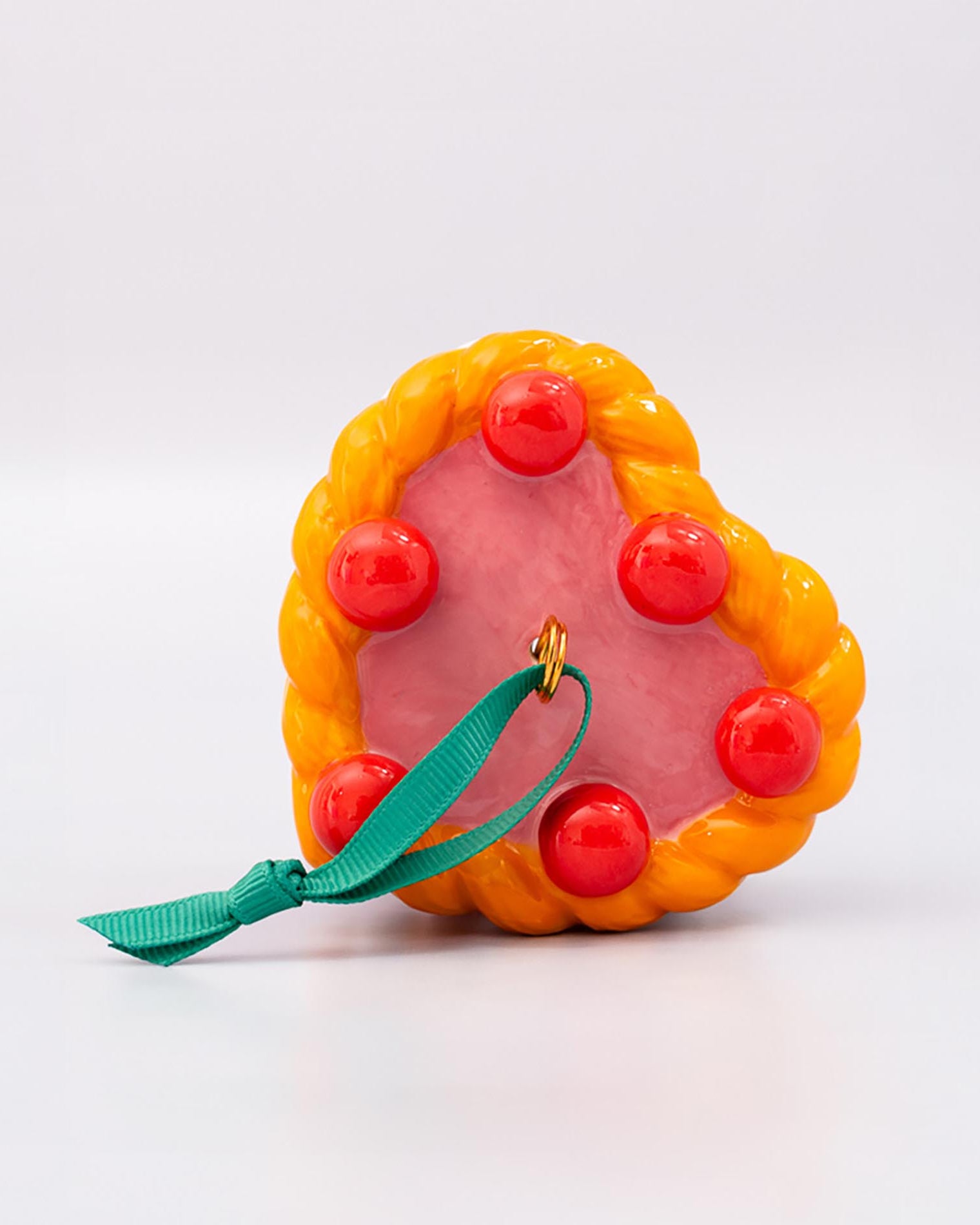Top view of ornament cake with pink filling, orange and white striped sides, and red cherries on a white background