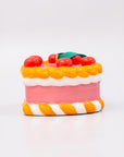 Ornament cake with pink filling, orange and white striped sides, and red cherries on a white background