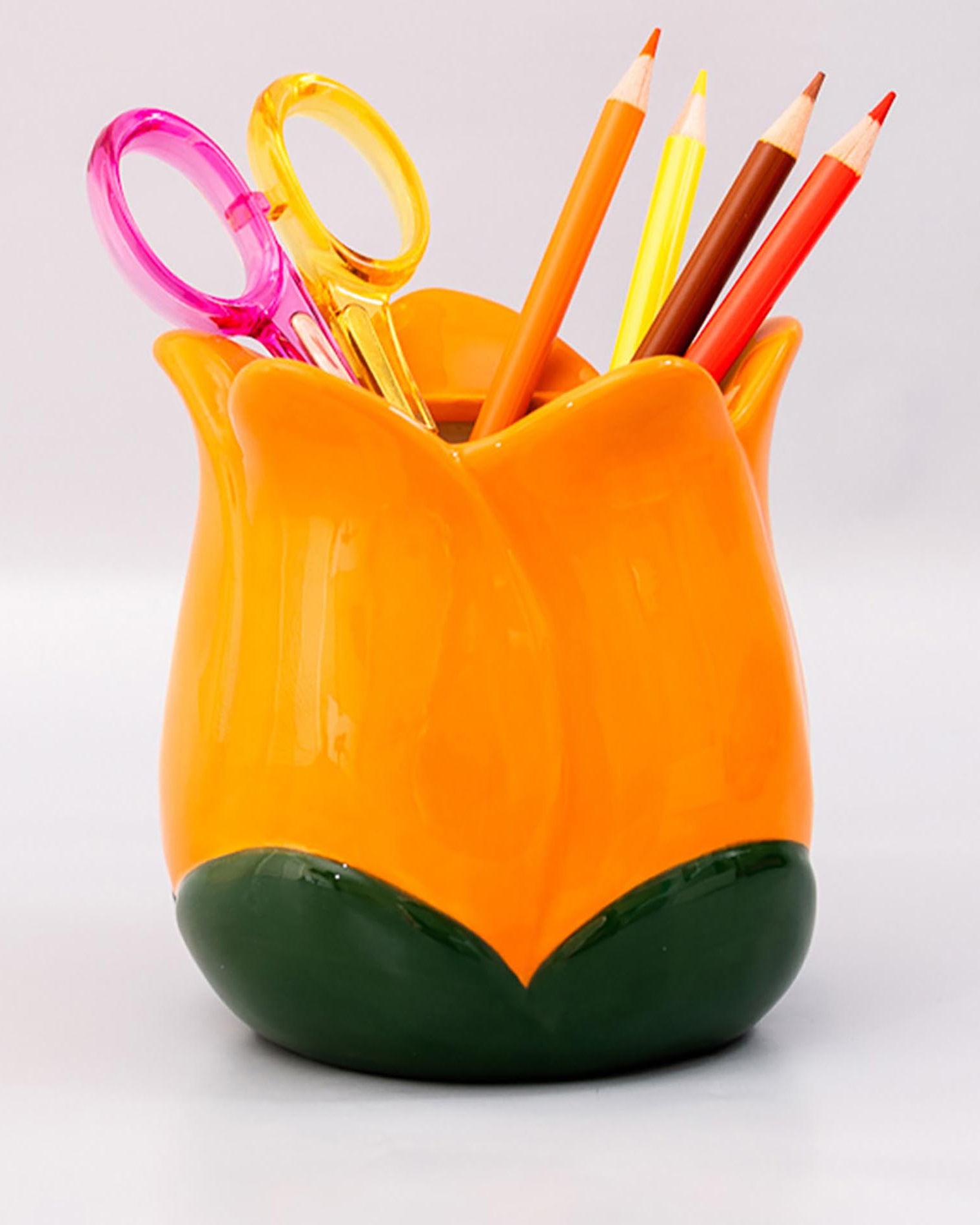 Orange tulip-shaped pen holder with colorful stationery items on a white background