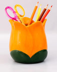 Orange tulip-shaped pen holder with colorful stationery items on a white background