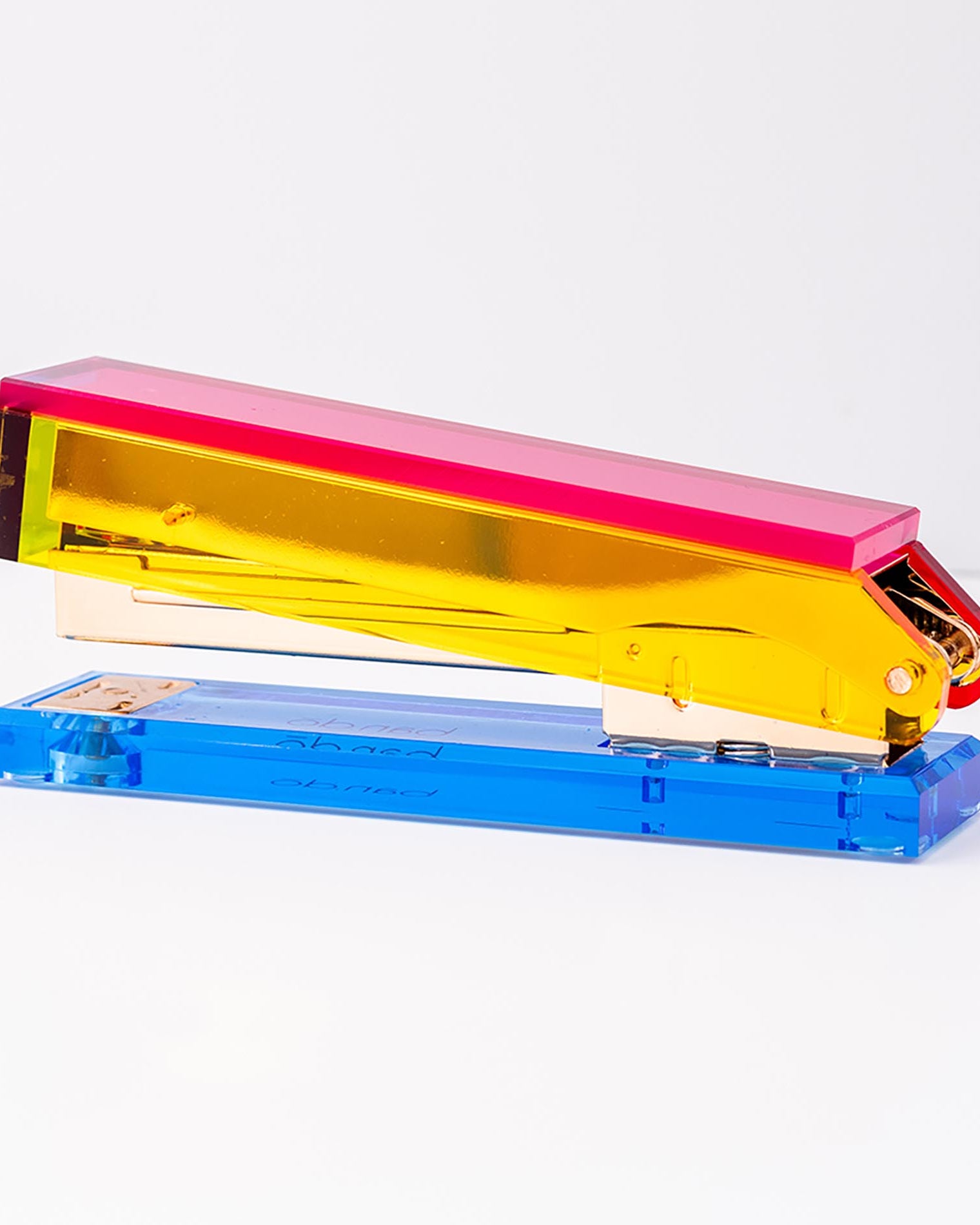 Colorful stapler with pink top, yellow middle, and blue base on a white background