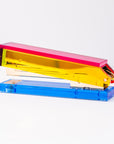 Colorful stapler with pink top, yellow middle, and blue base on a white background