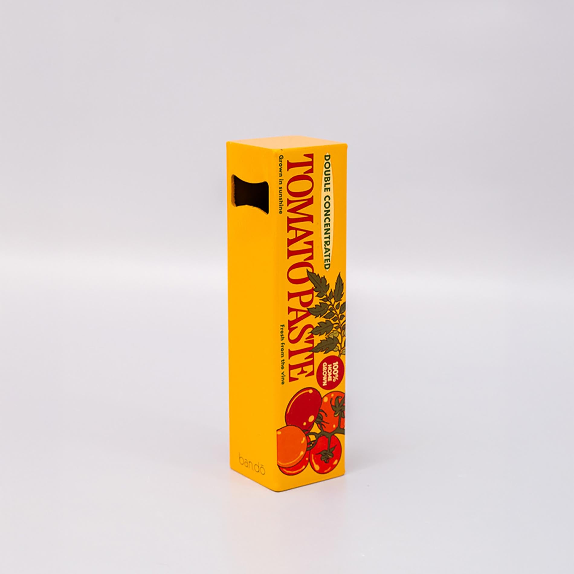 Reverse side of yellow box of tomato paste bottle opener with red tomatoes on a white background