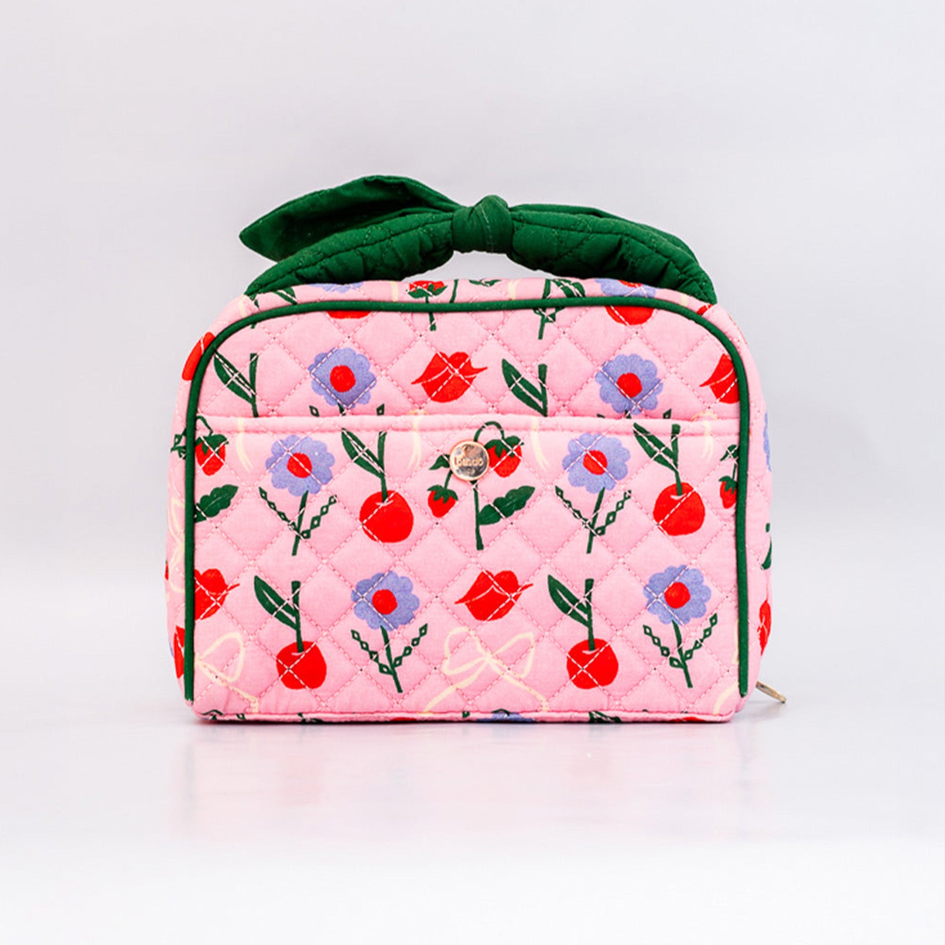 Pink quilted bag with floral and cherry pattern on a white background