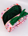 Pink floral-patterned pouch with a green bow on a light gray background