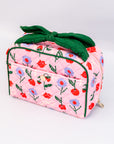 Pink floral-patterned bag with a green bow on a white background