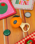Orange ball with a bottle cap and toy on a wooden surface