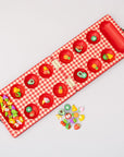 Red checkered mancala board with fruit-themed items on a light gray background
