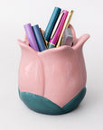 Pink tulip-shaped pen holder with colorful pens on a white background