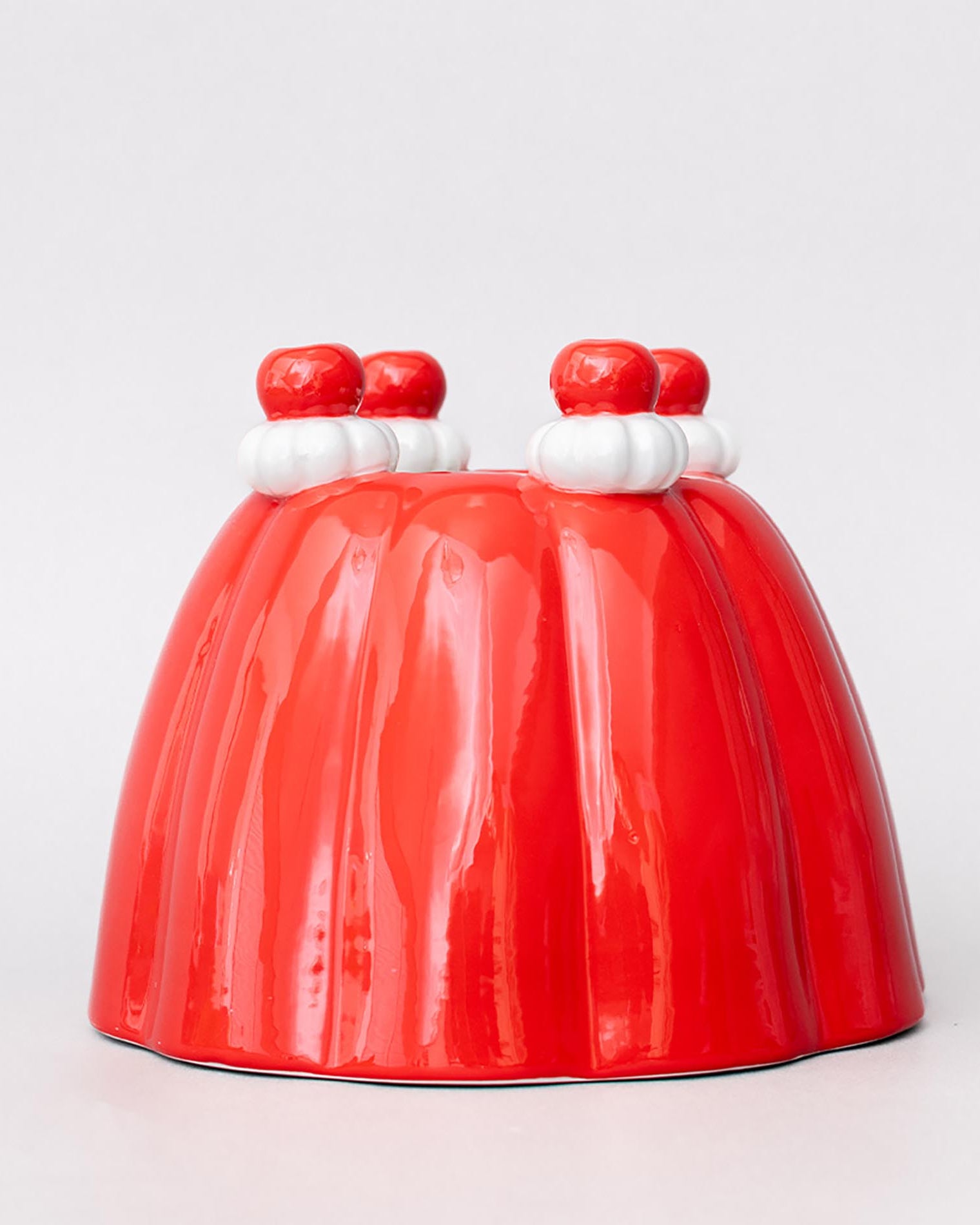 Red jelly mold vase with white and red decorations on a light gray background
