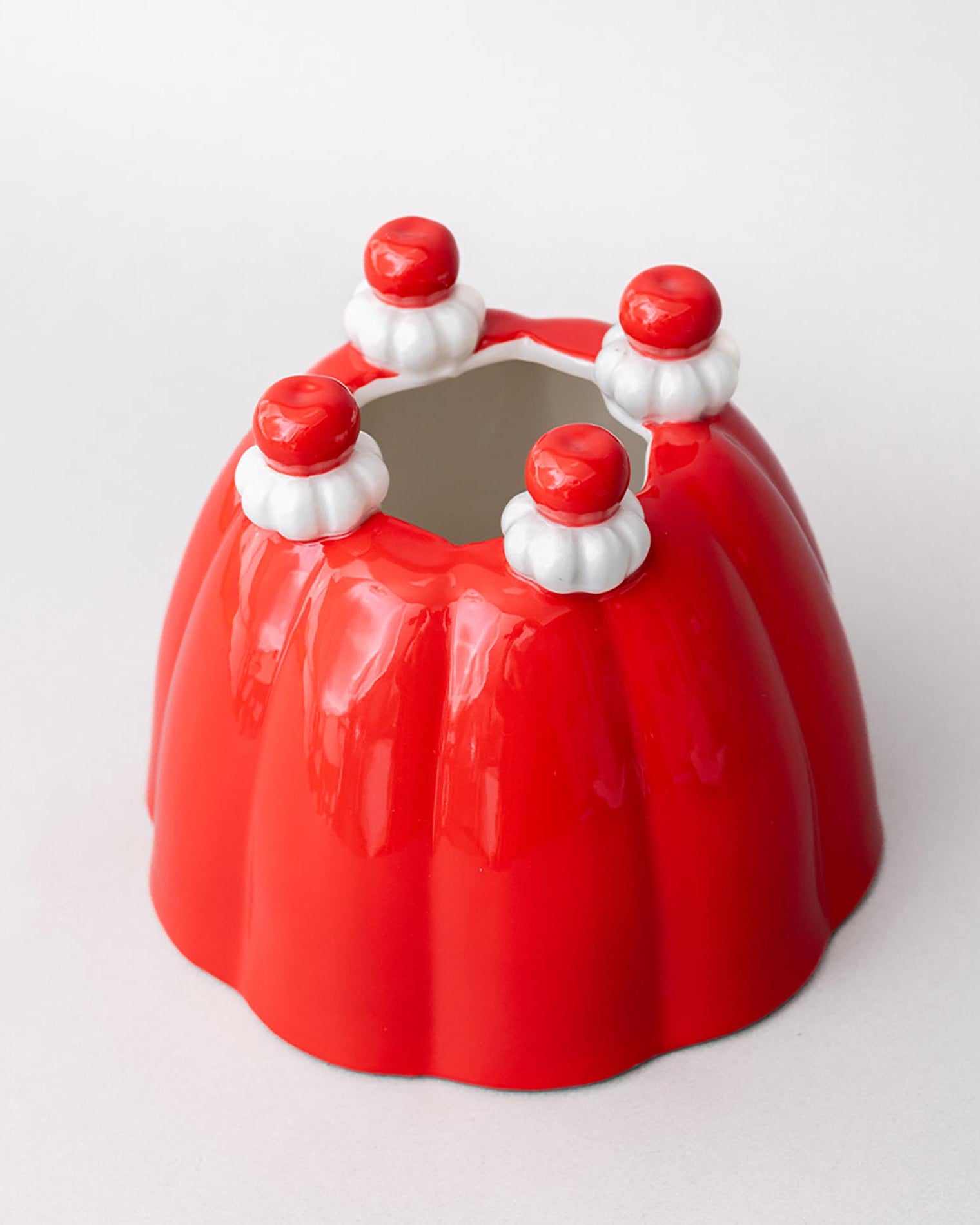 Red jelly mold vase with white and red decorative elements on a white background