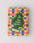 Colorful checkered tin with a green tree design and text on a gray background