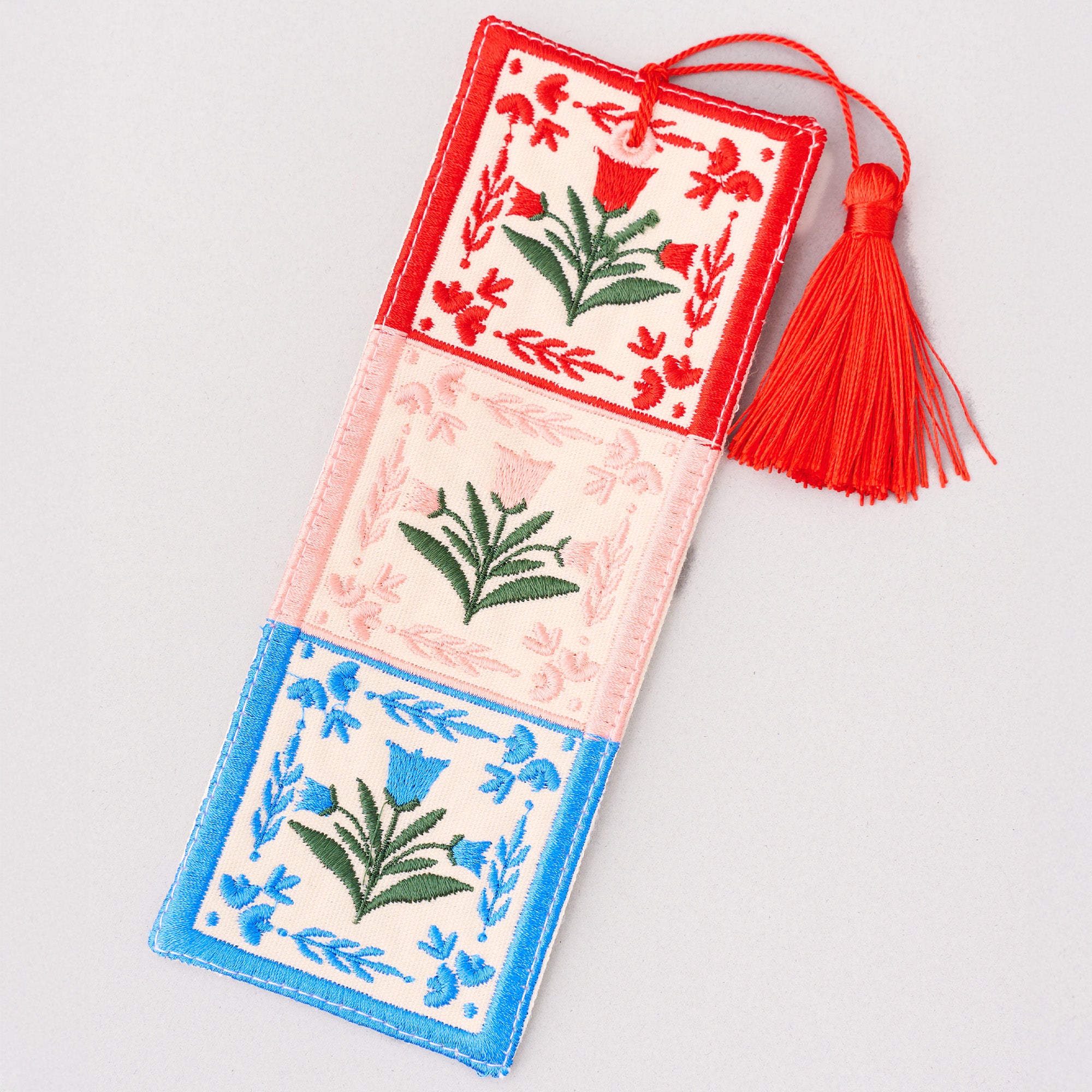 Decorative bookmark with floral patterns and a red tassel on a light gray background