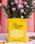yellow pasta box vase with purple flowers inside