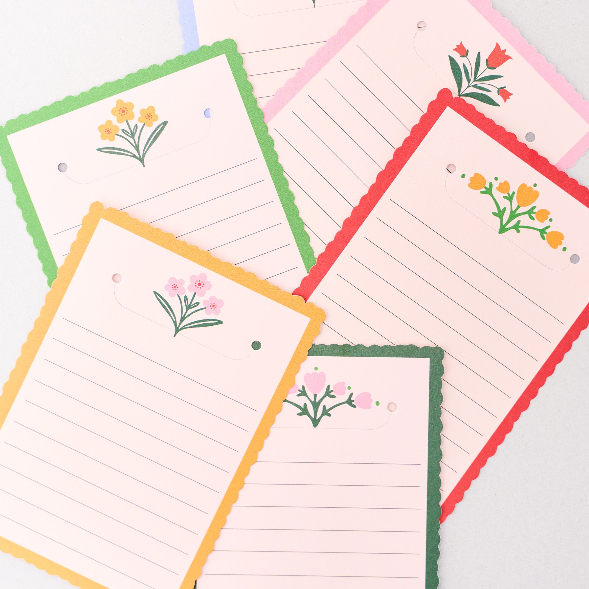 Set of lined notepads with floral designs on colorful borders.