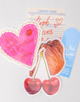 Set of colorful stickers with heart, cherry, library card, pastry, and bookmark on a light gray background.