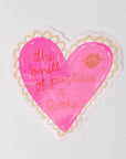 Pink heart-shaped sticker with text and a lip print on a white background