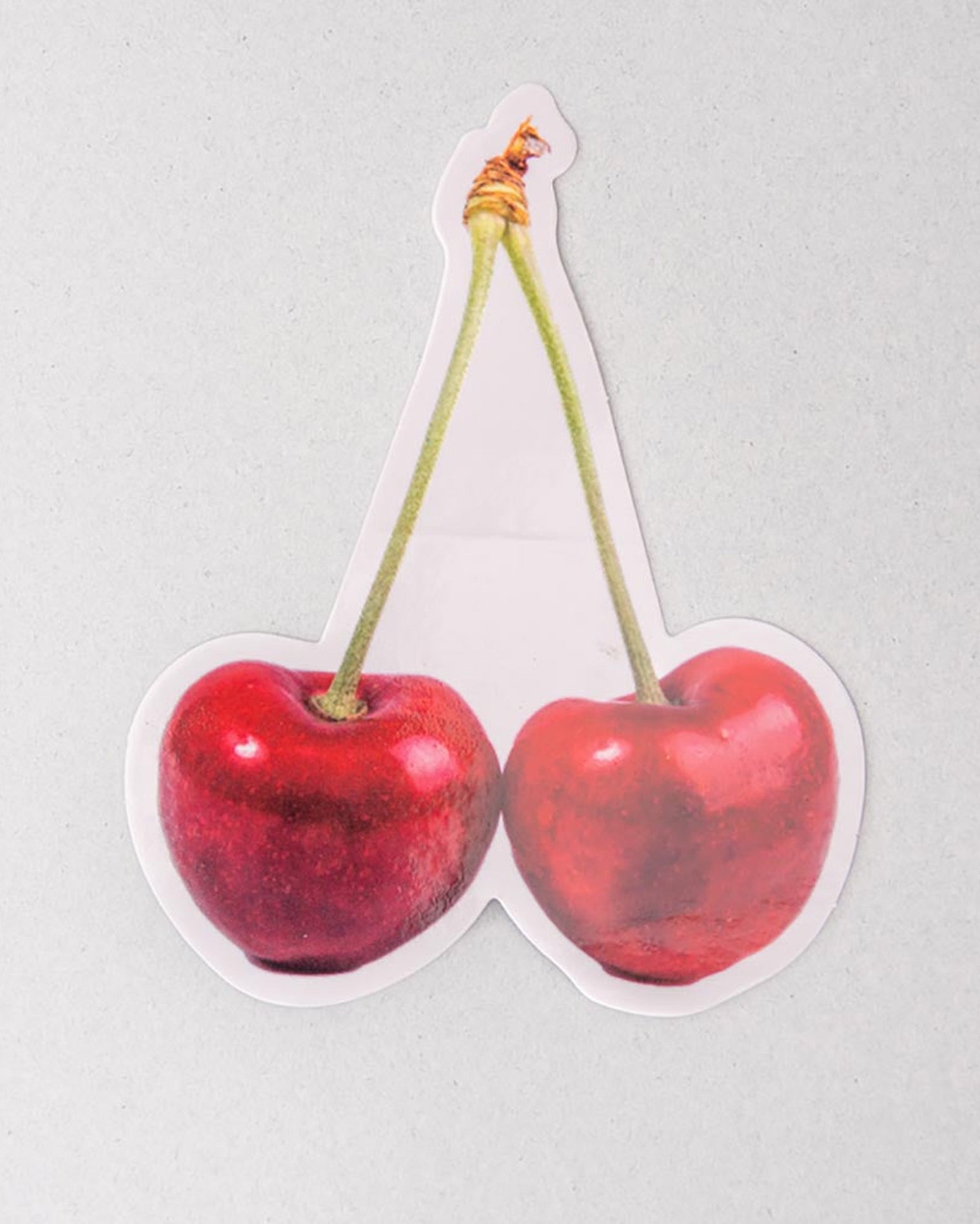 Sticker of two red cherries on a light gray background