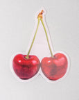 Sticker of two red cherries on a light gray background