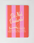 Notebook with pink and red striped cover and 'Do Not Disturb!' text on a white background