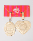 Two gold luggage tags, one oval and one heart-shaped, on a red and pink striped 'Badget Luggage Tags' card.