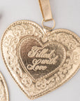 Gold heart-shaped pendant with 'Filled with Love' engraving on a light gray background