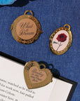 Three decorative bookmarks with engraved text and a rose on a blue fabric background.