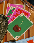 Playing cards with a cherry design on a wooden surface