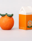 Orange-shaped container with green top next to its packaging on a white background