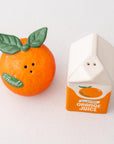 Orange-shaped salt and pepper shaker with a carton-shaped orange juice container on a white background