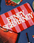 Striped pouch with 'Fancy Schmancy' text on a blue surface with accessories.