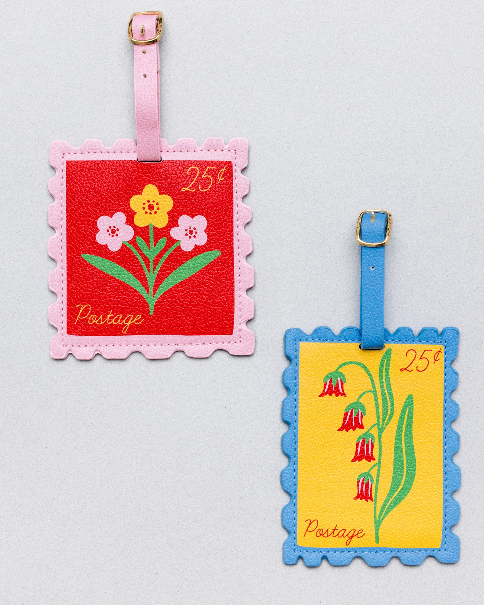 Two vintage-style postage luggage tags on a light gray background. One tag has a pink border, a red center, and pink, yellow, and white flowers with a pink strap and gold buckle.