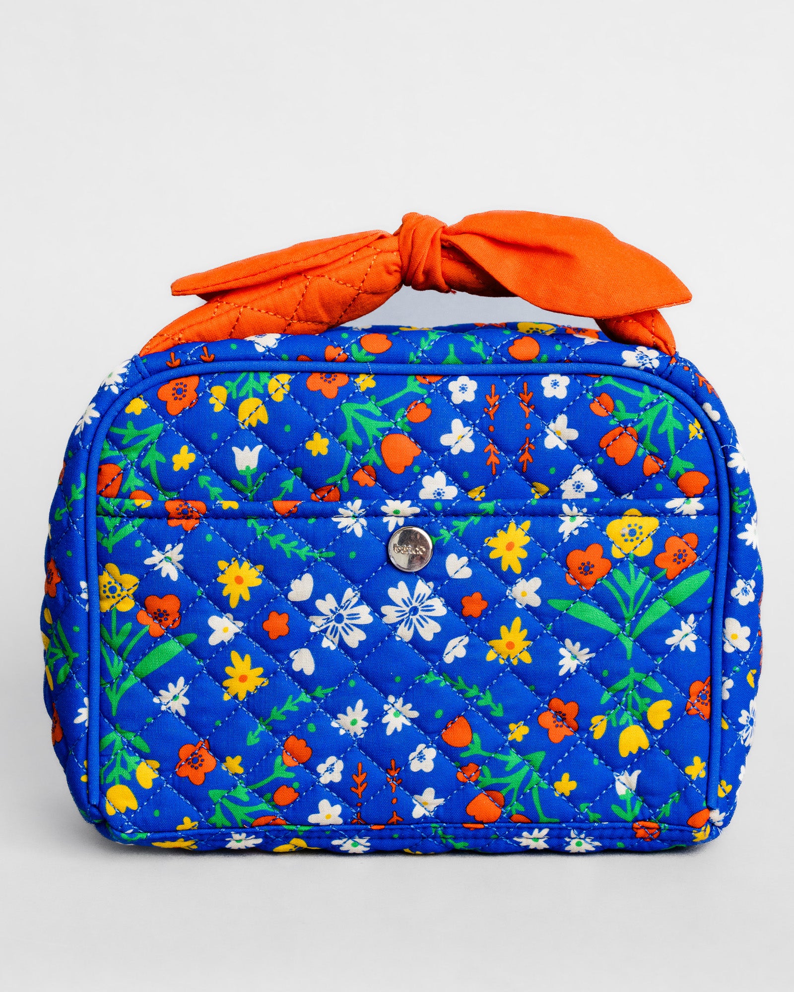 A quilted cosmetic bag in a vibrant blue floral print with a bright orange fabric handle tied in a bow, set against a plain light gray background.