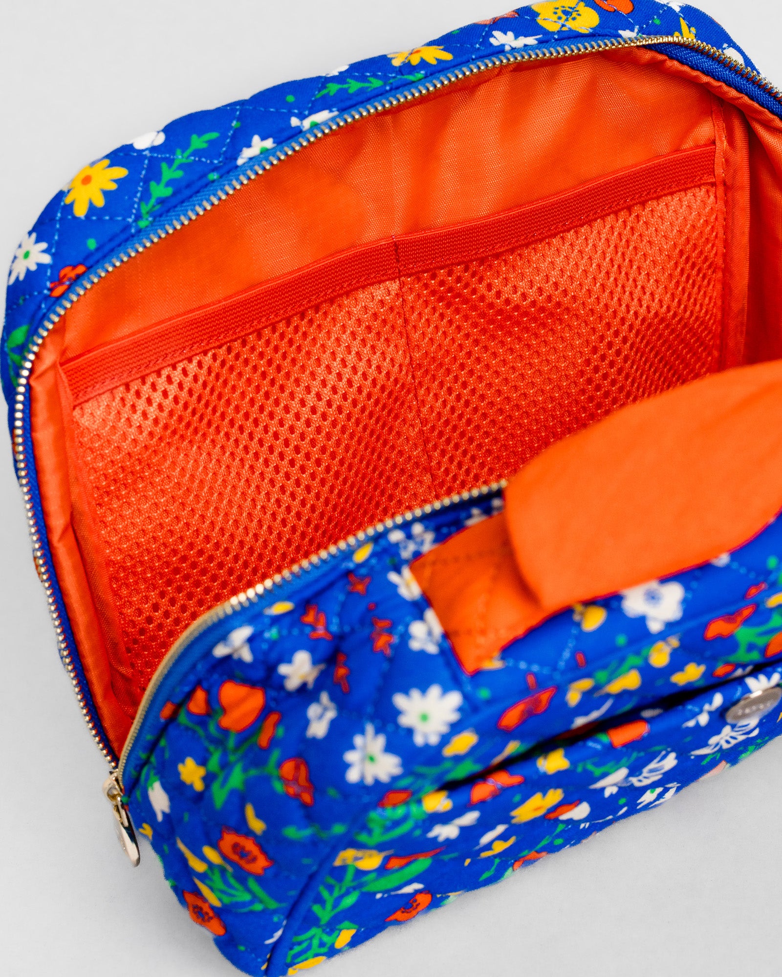 A blue floral zippered pouch with a bright orange mesh interior and matching orange fabric lining, shown open on a light gray background.