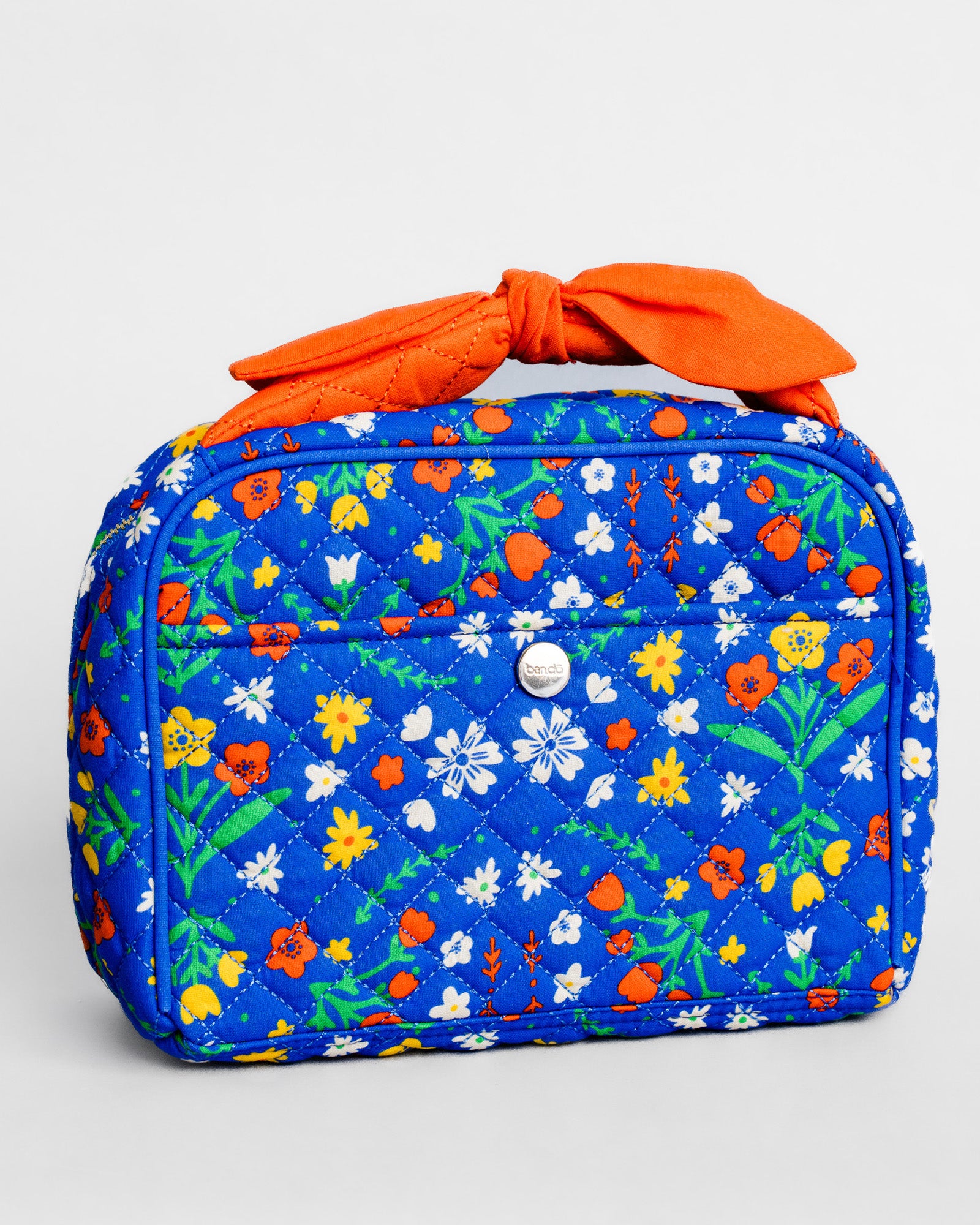 A quilted cosmetic bag with a vibrant blue background and a colorful floral print, featuring a bright orange fabric handle tied in a bow and a silver snap button on the front.