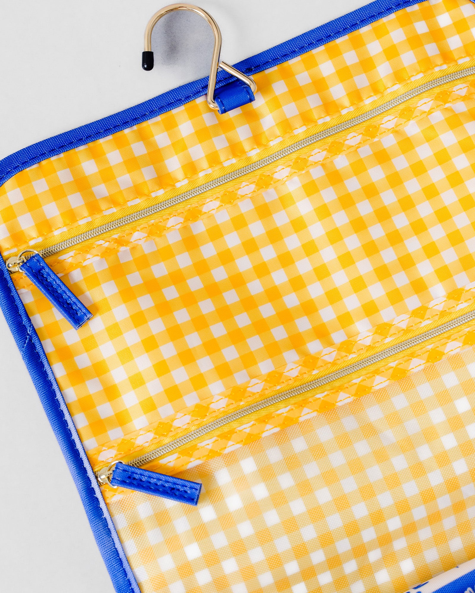 Yellow and white gingham hanging organizer pouch with blue trim and zipper pulls, shown on a light gray background.