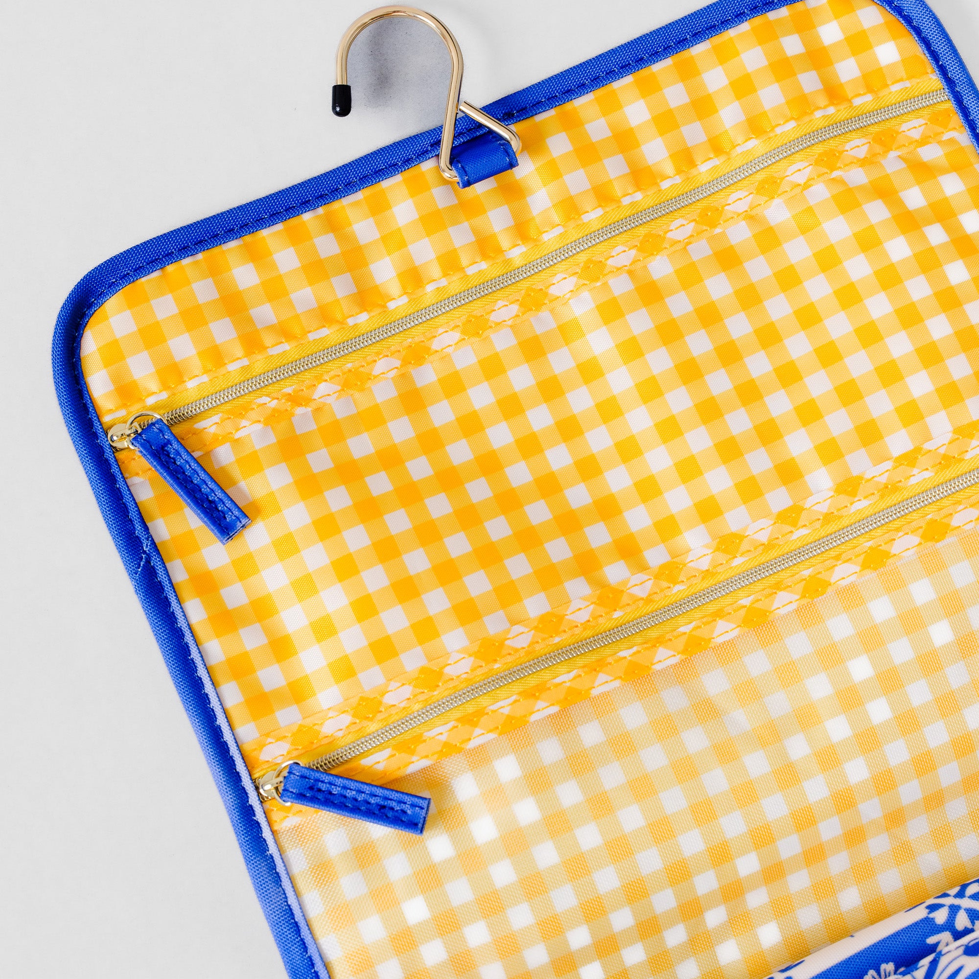 Yellow and white gingham hanging organizer pouch with blue trim and zipper pulls, shown on a light gray background.