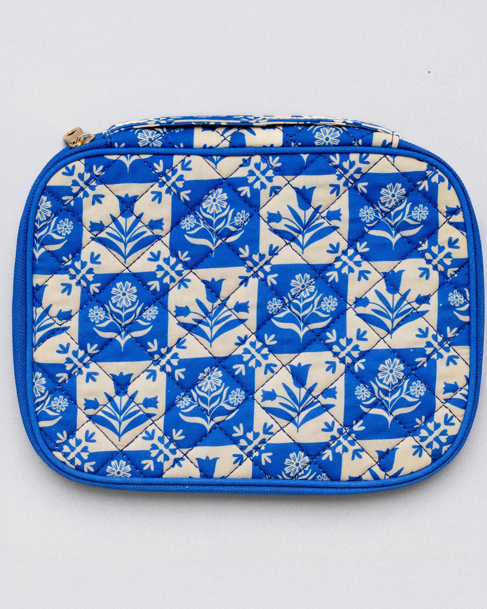 A quilted zippered pouch featuring a blue and cream floral tile pattern, photographed flat against a light gray background.