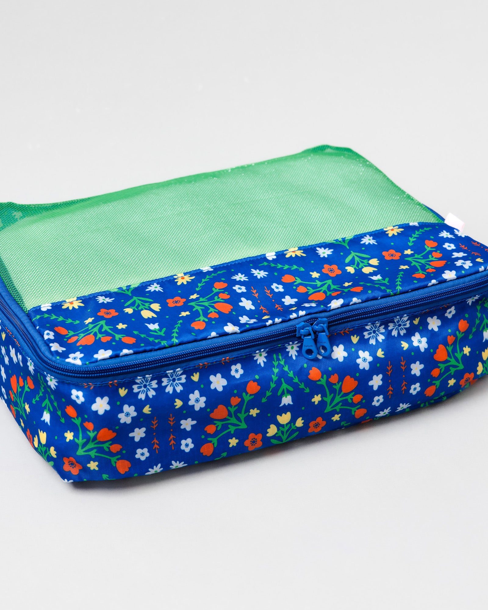 A rectangular zippered travel organizer bag with a blue floral patterned exterior and a green mesh top window, shown on a light gray background.