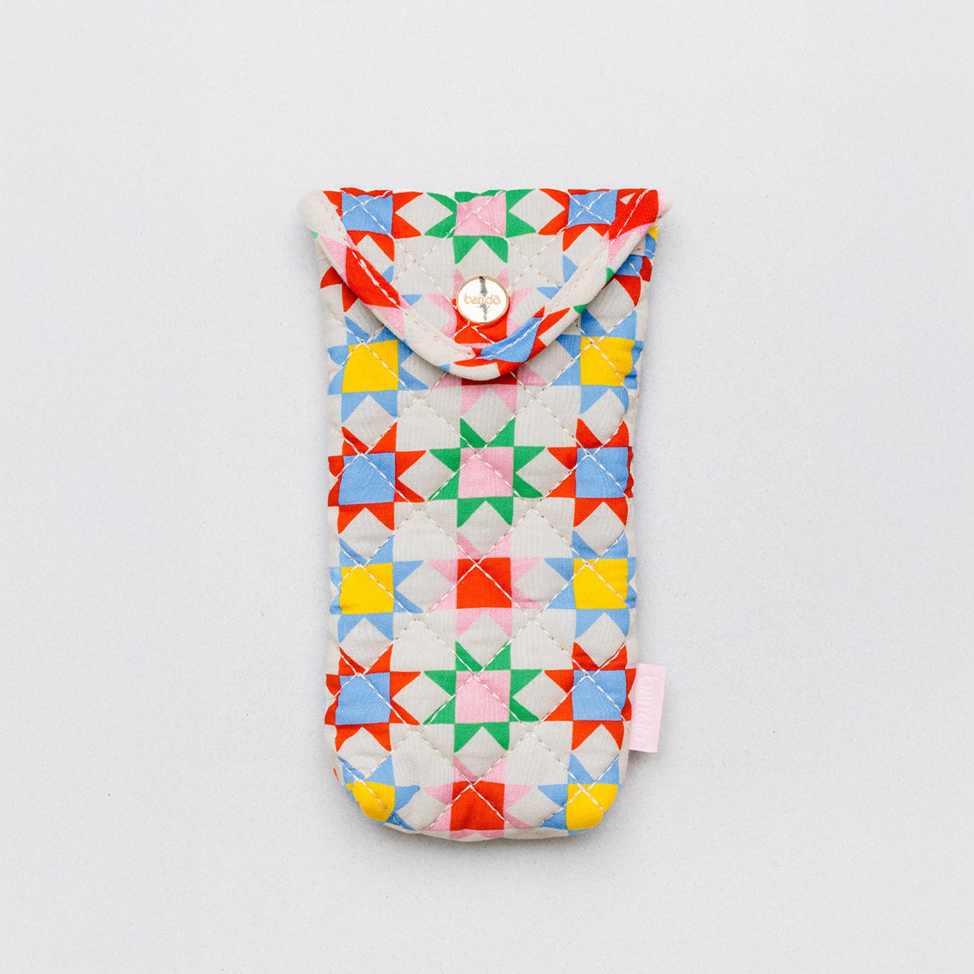 A fabric pouch with a colorful geometric star pattern on a light background, featuring a snap button closure at the top and a small pink tag on the side, photographed on a neutral light gray background.